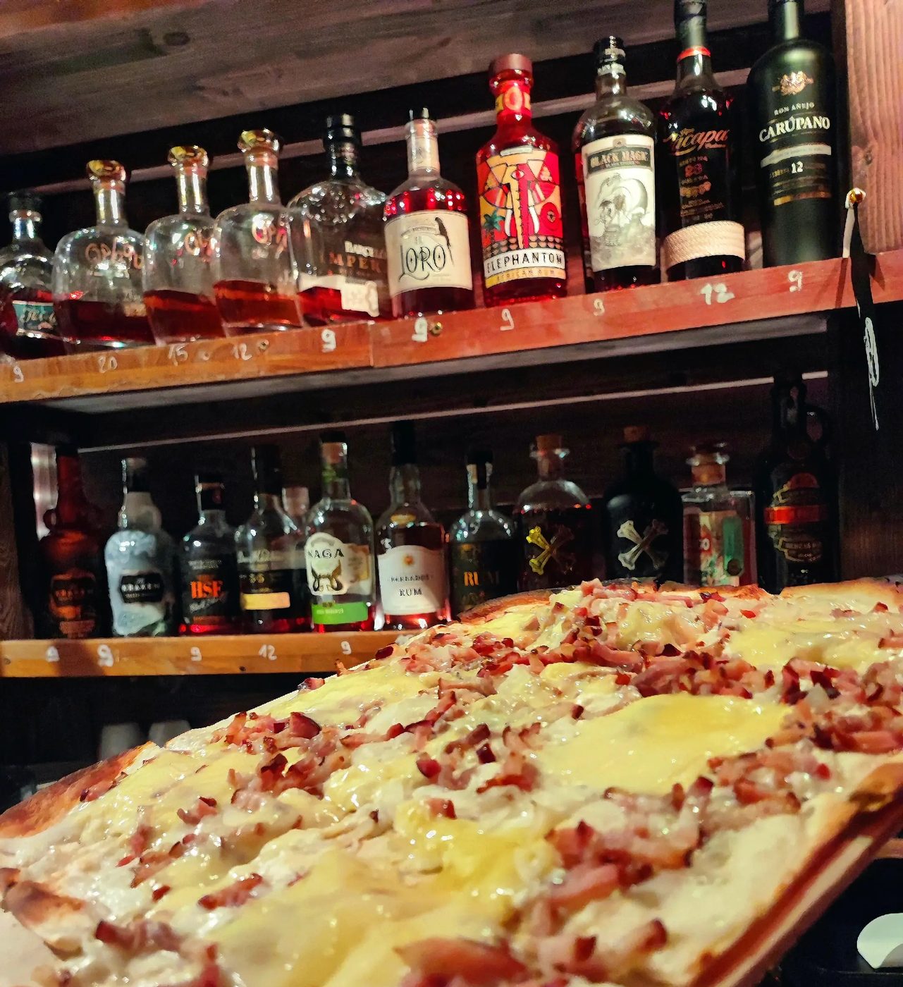 Tarte flambée lardons devant le mur de rhums du Kraken Colmar